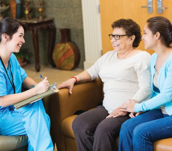 A dental hygienist discussing care plans with a resident and her family member in a lounge